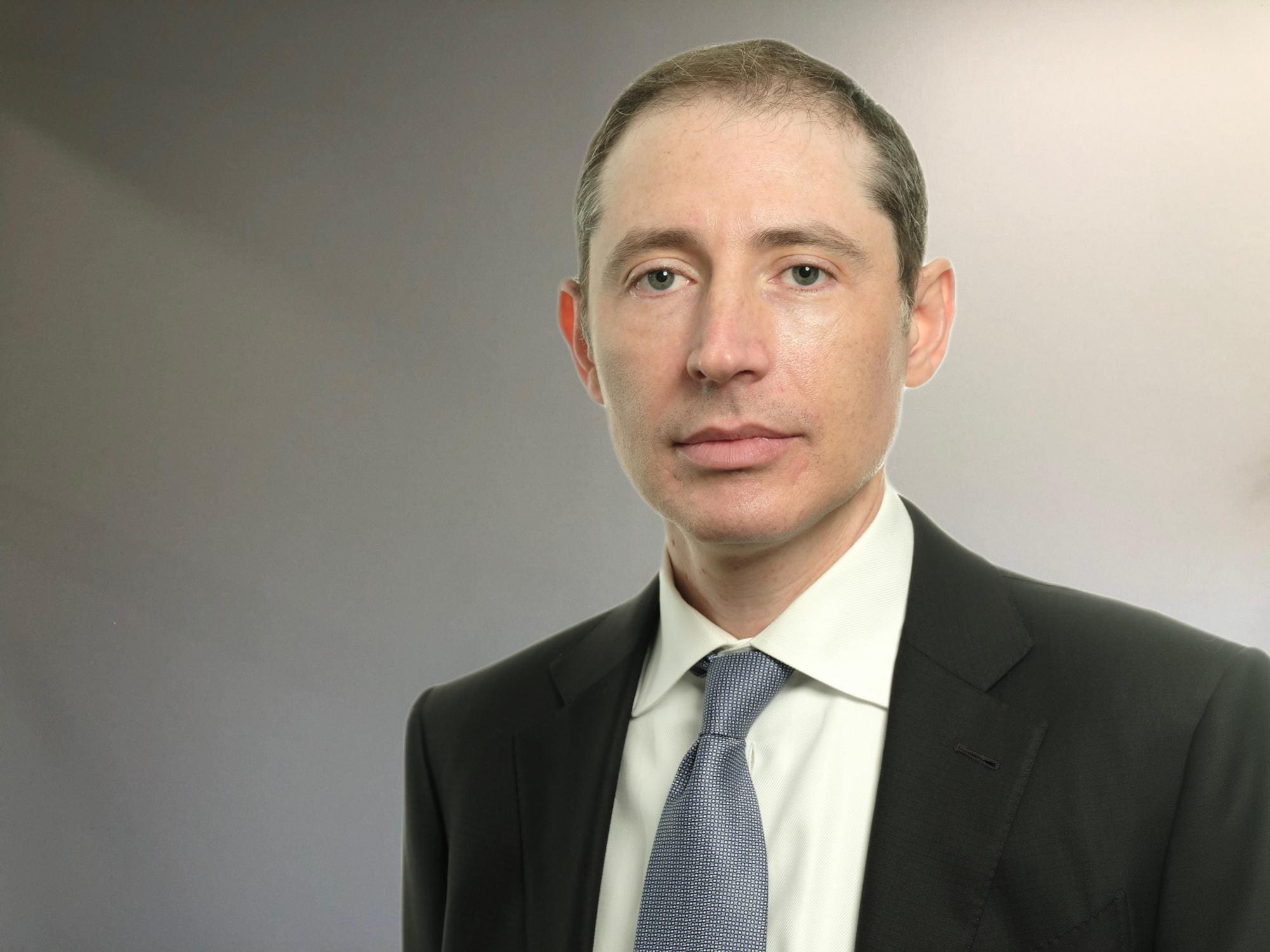 A man in suit and tie standing next to wall.