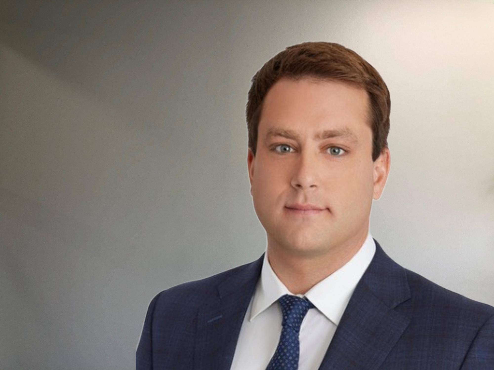 A man in a suit and tie standing next to a wall.