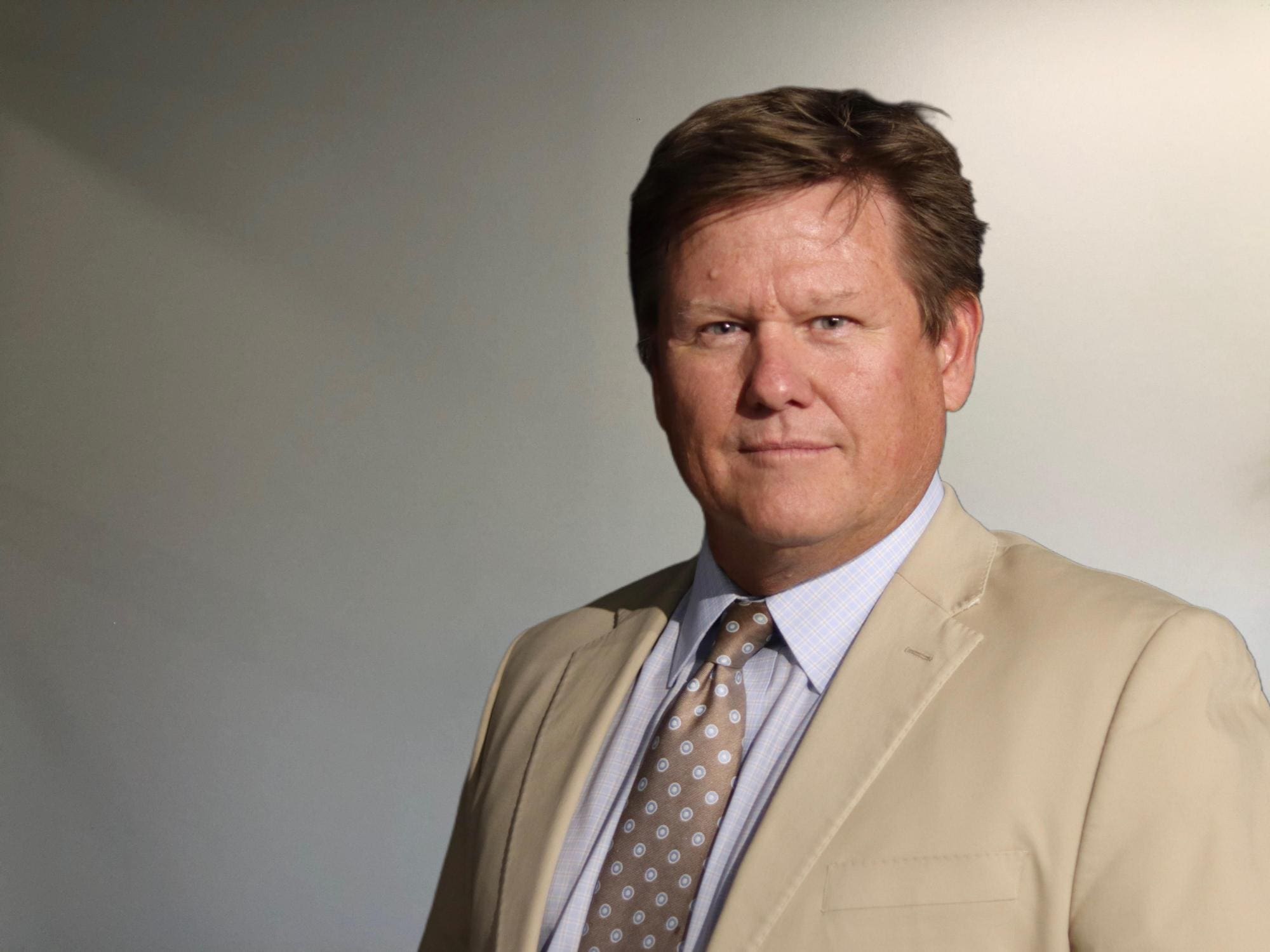 A man in a suit and tie standing next to a wall.