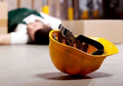 A man laying on the ground next to an orange hard hat.